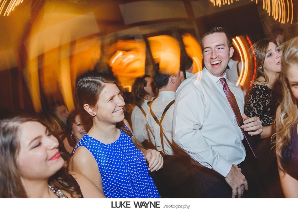 People at a party, laughing and dancing; a man in a white shirt and tie smiles broadly.