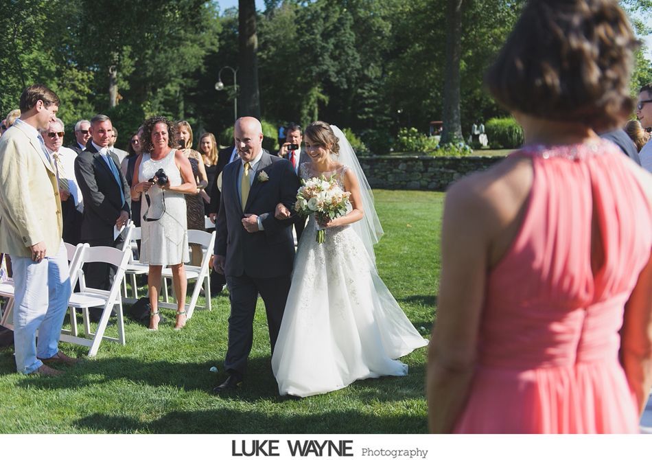 Bride walking down the aisle with her father at an outdoor wedding.