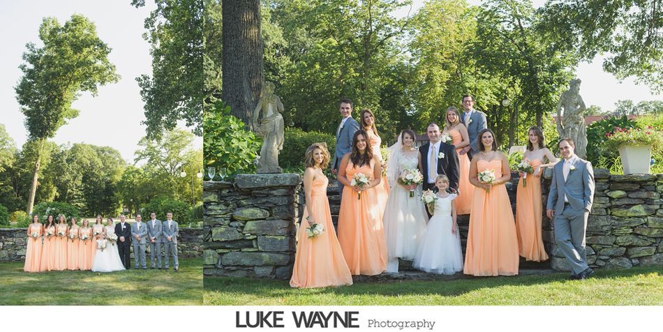 Wedding party posing outdoors; Bride and groom with bridesmaids in peach dresses and groomsmen in gray suits.