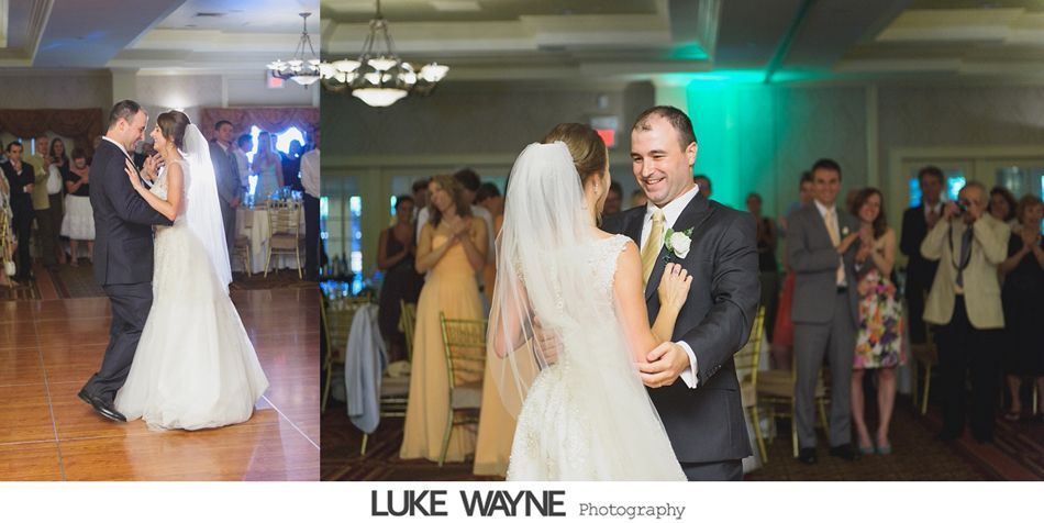 Bride and groom share a dance at their wedding reception, surrounded by guests clapping.