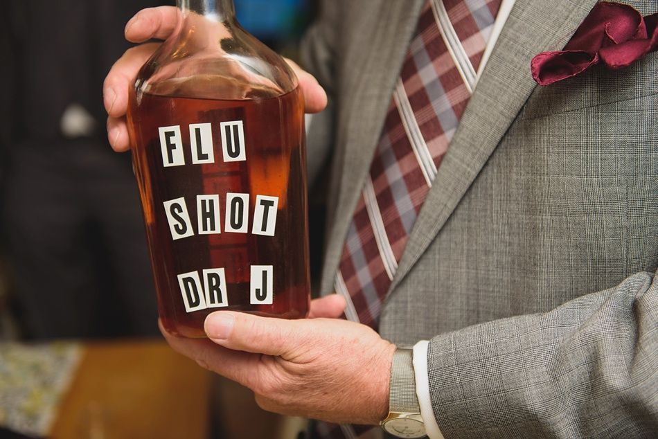 Man in suit holds a liquor bottle labeled 