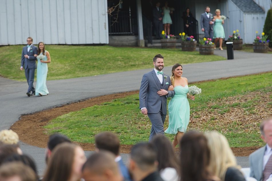 Wedding party walking outdoors; couple in foreground, others in background, all wearing formal attire.