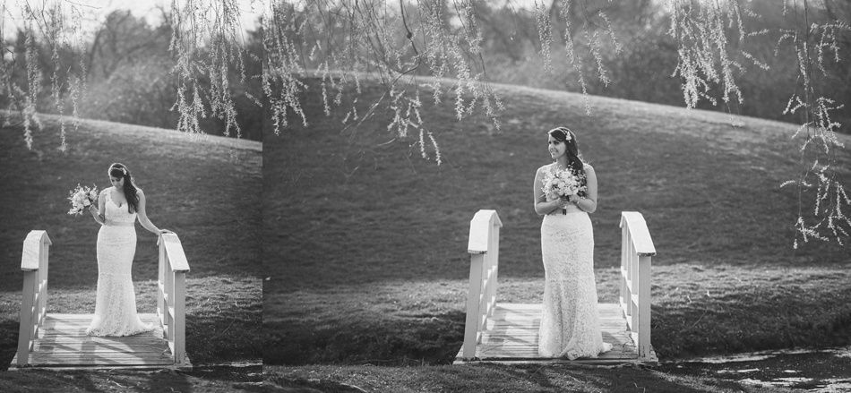 Bride in a white dress stands on a small bridge holding flowers. Scenic outdoor setting with weeping willow trees.