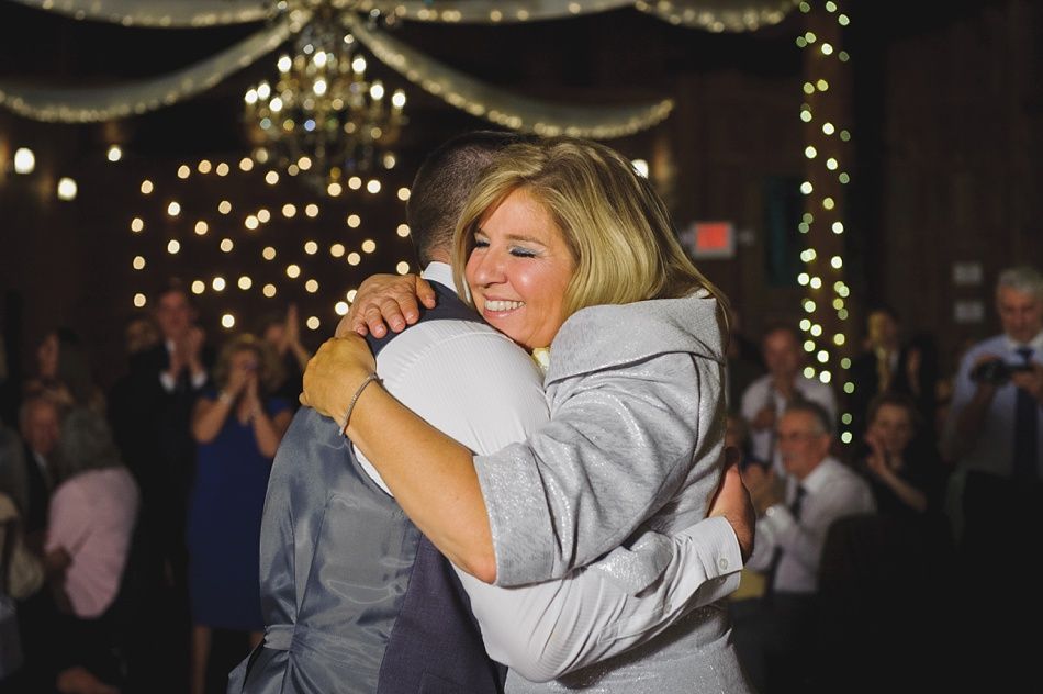Woman hugging person, smiling at event with lights in background.