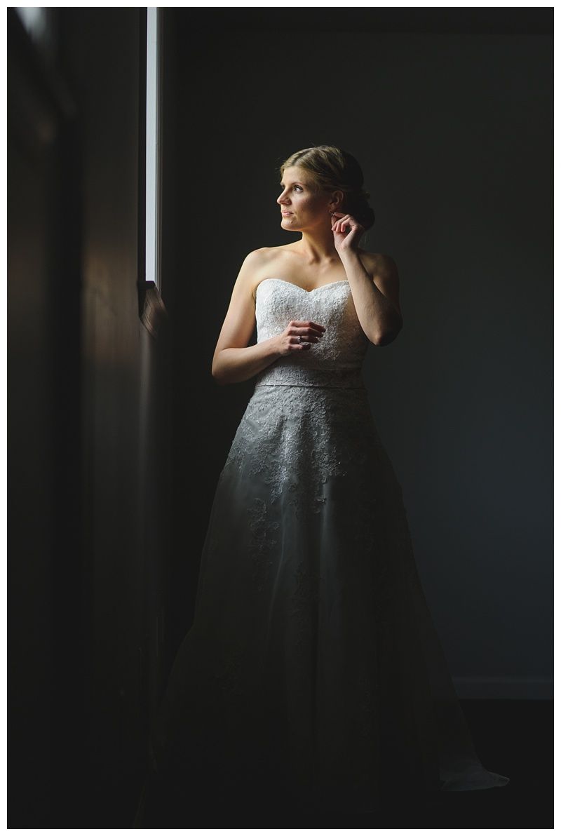 Bride with arms up, making a funny face, groom looking at his hand, cake cutting in background.