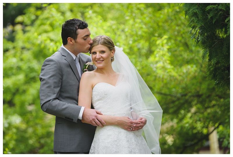 Bride with arms up, making a funny face, groom looking at his hand, cake cutting in background.