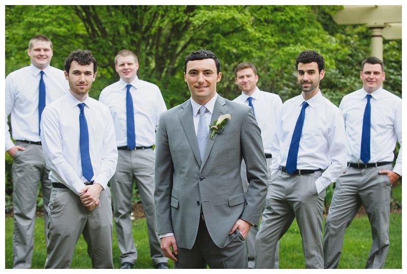 Bride with arms up, making a funny face, groom looking at his hand, cake cutting in background.