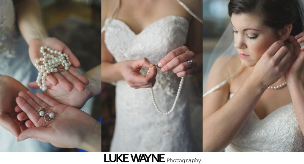 Bride in white dress, putting on pearl earrings and necklace before the wedding.