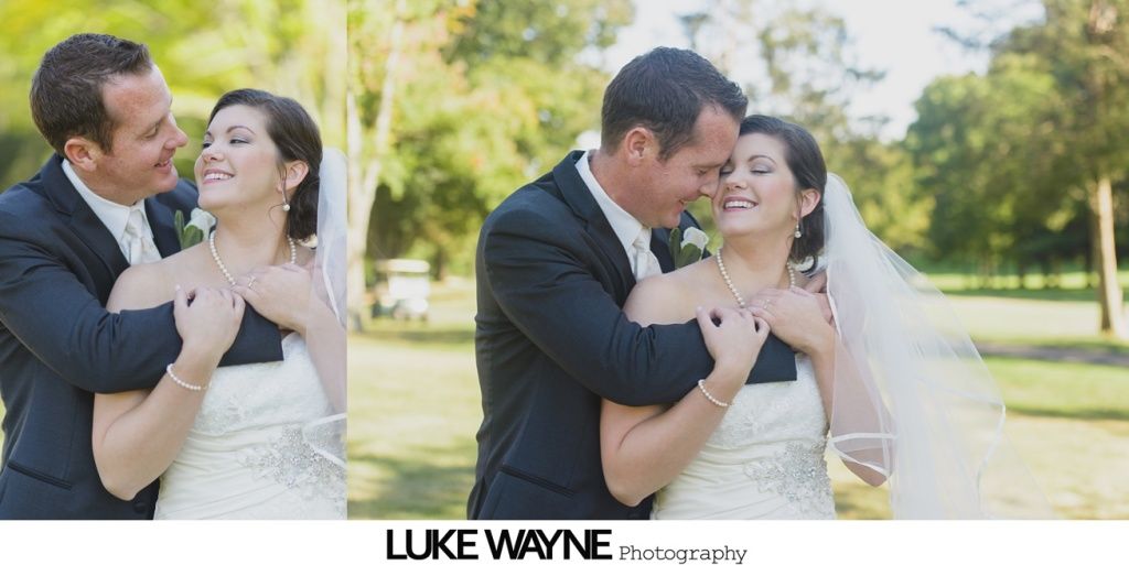 Smiling couple embracing outdoors on a sunny day. Wedding attire, man's arms around woman.