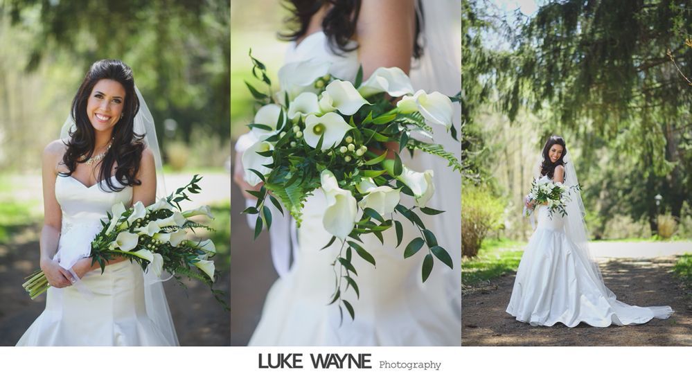 Bride in white dress, holding bouquet, poses outdoors under trees.