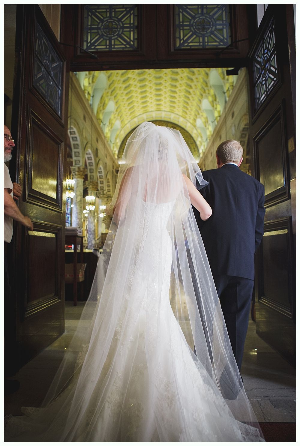 Bride with arms up, making a funny face, groom looking at his hand, cake cutting in background.