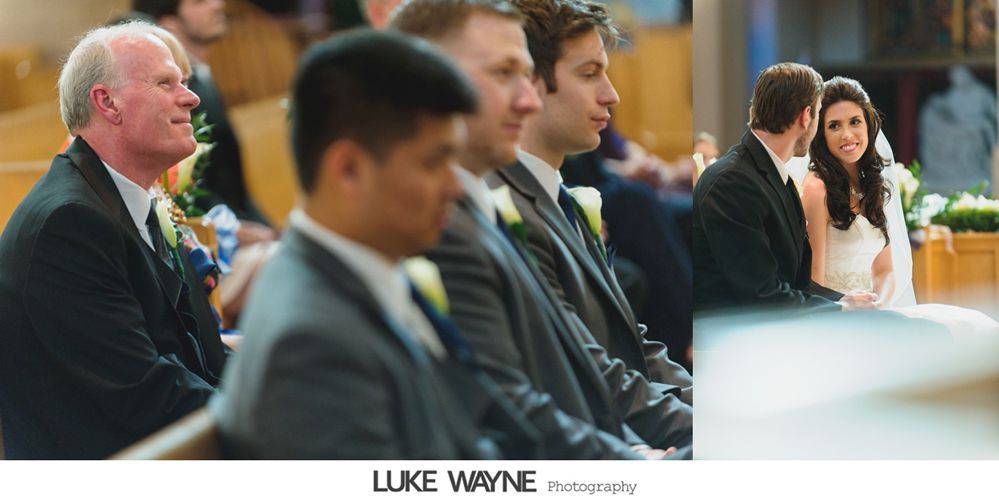 People in formal attire seated in a church; bride and groom in the background, groomsmen in the foreground.