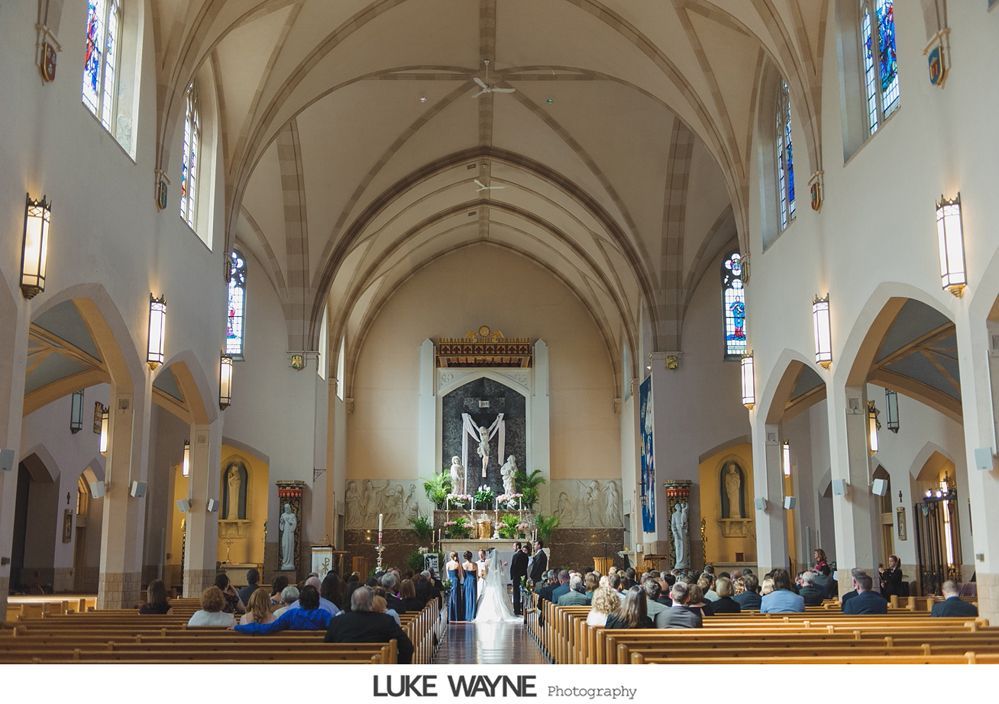 Wedding ceremony inside a church with a bride and groom at the altar, guests seated in pews.