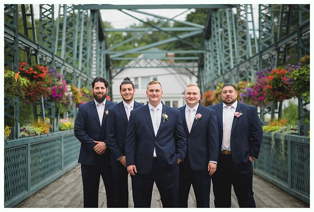 Bride with arms up, making a funny face, groom looking at his hand, cake cutting in background.