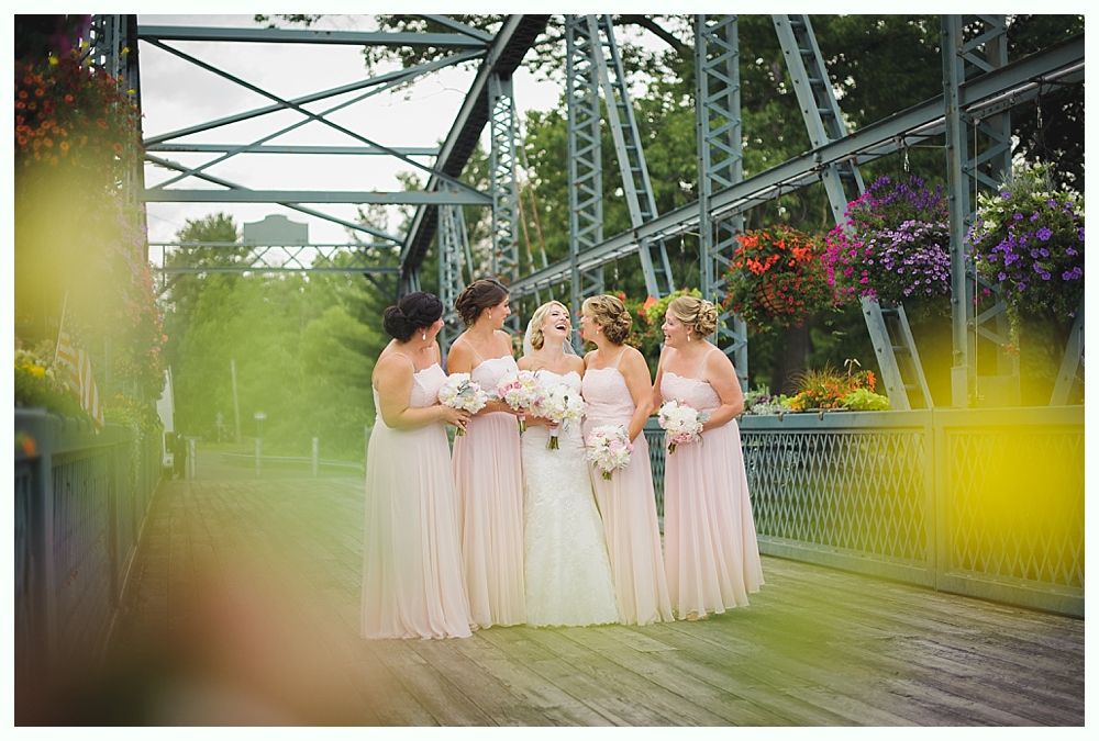 Bride with arms up, making a funny face, groom looking at his hand, cake cutting in background.