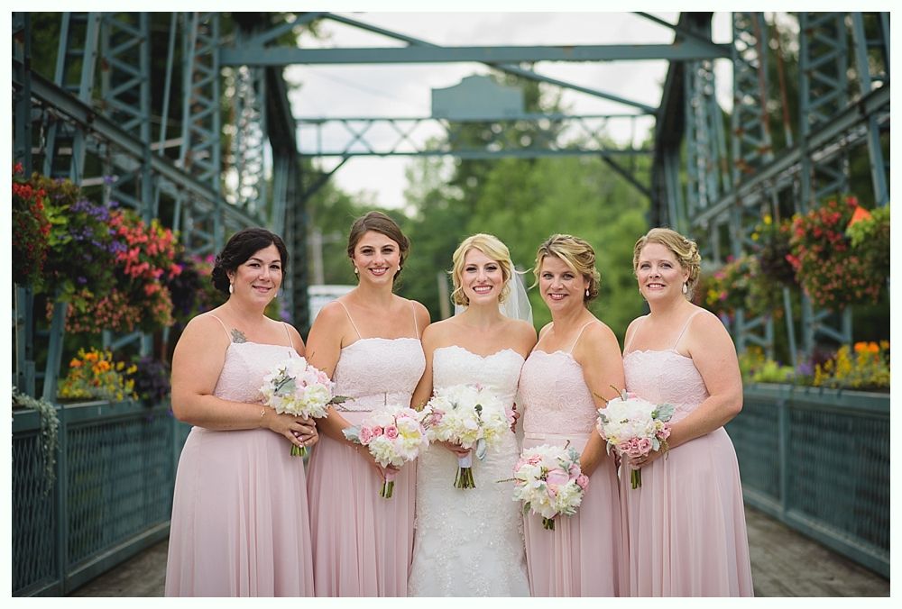 Bride with arms up, making a funny face, groom looking at his hand, cake cutting in background.