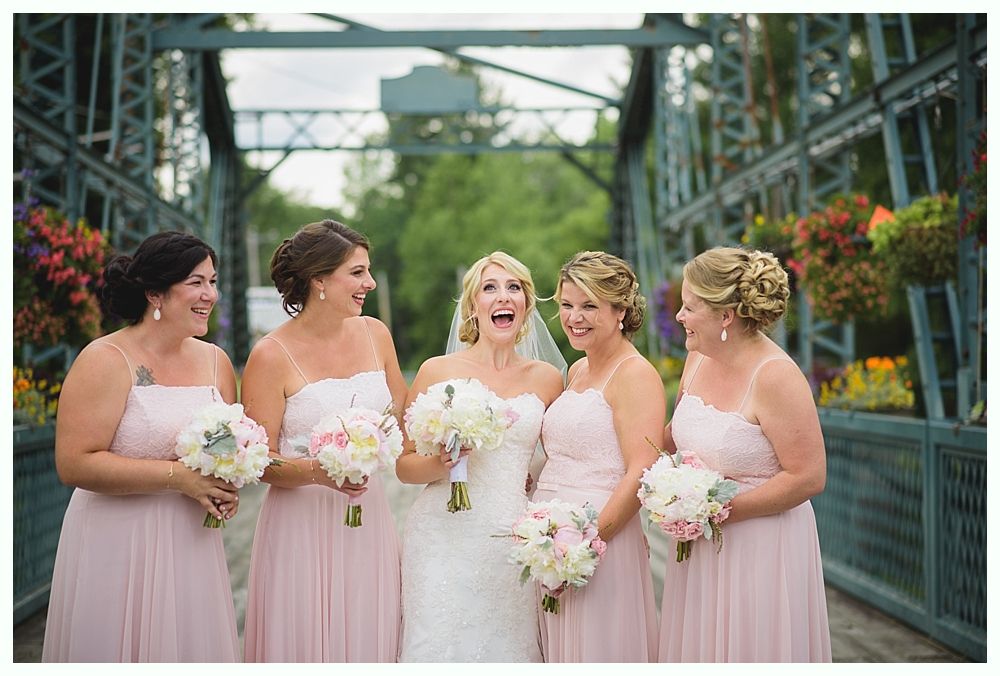 Bride with arms up, making a funny face, groom looking at his hand, cake cutting in background.