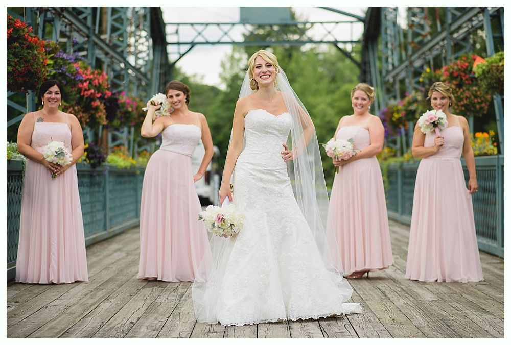 Bride with arms up, making a funny face, groom looking at his hand, cake cutting in background.