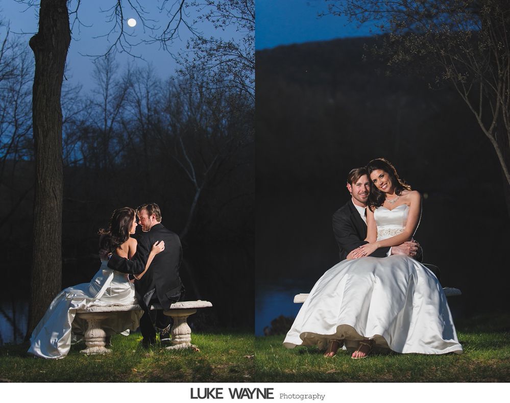 Bride and groom sit on a bench at night, illuminated by the moon, embracing in a romantic pose.
