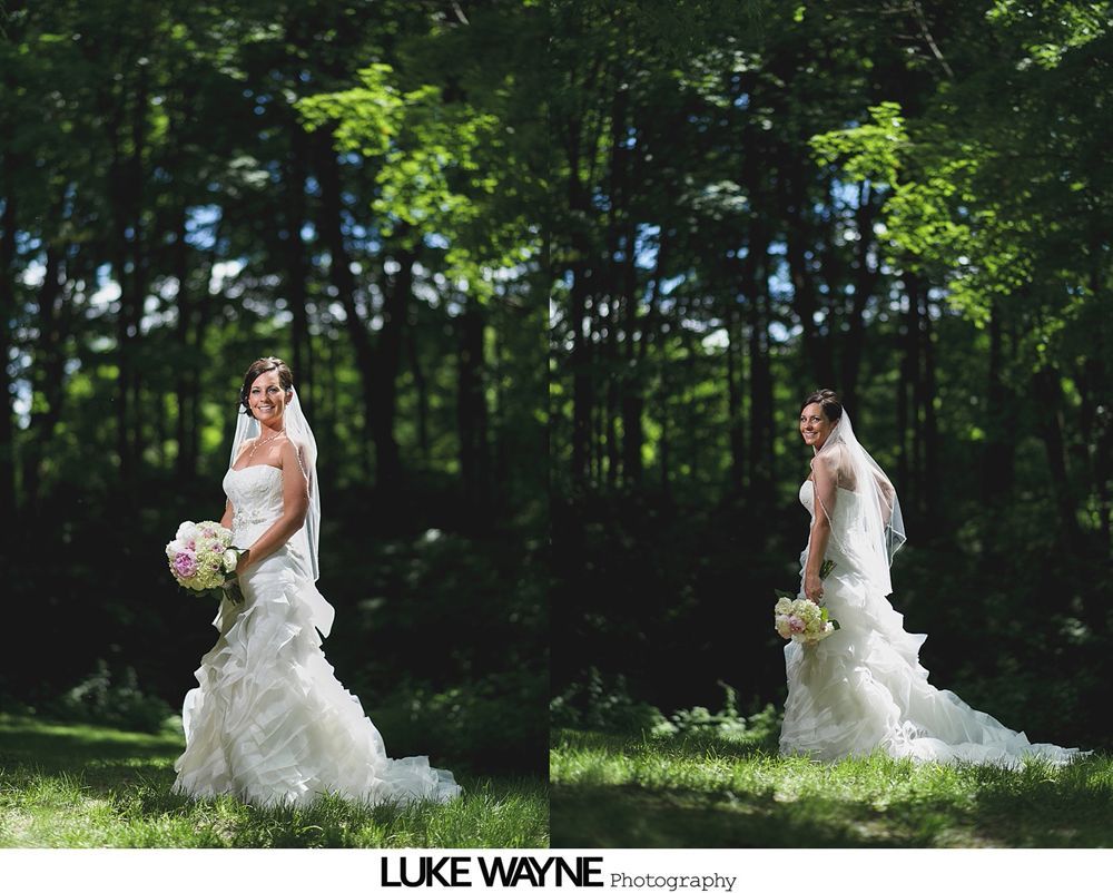 Bridesmaids in pastel dresses pose with bride outdoors near a building with lush green trees.