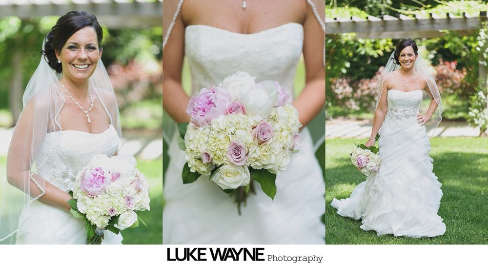 Bride in a white lace wedding dress holding a bouquet. She's outdoors on a pathway, smiling.