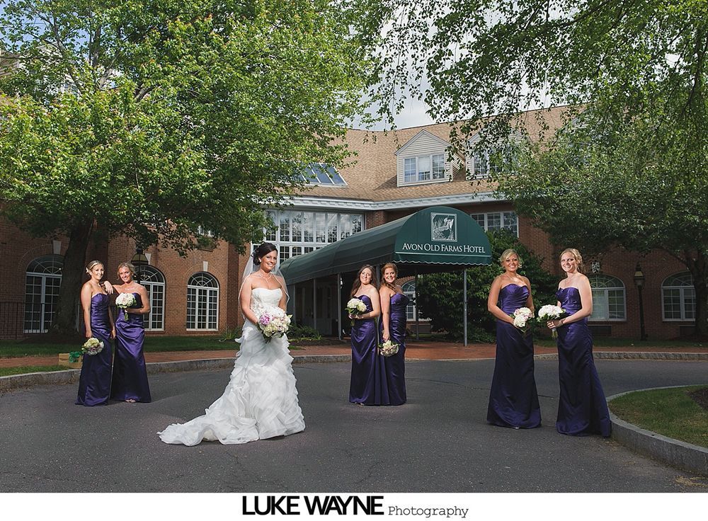 Bridesmaids posing for a group photo in a garden, holding bouquets and smiling.