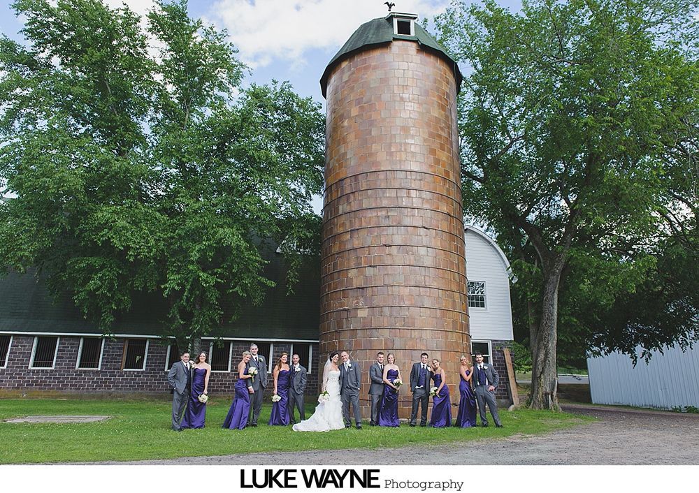 Bride and groom on a road. Man hugs woman, smiles, and holds flowers.