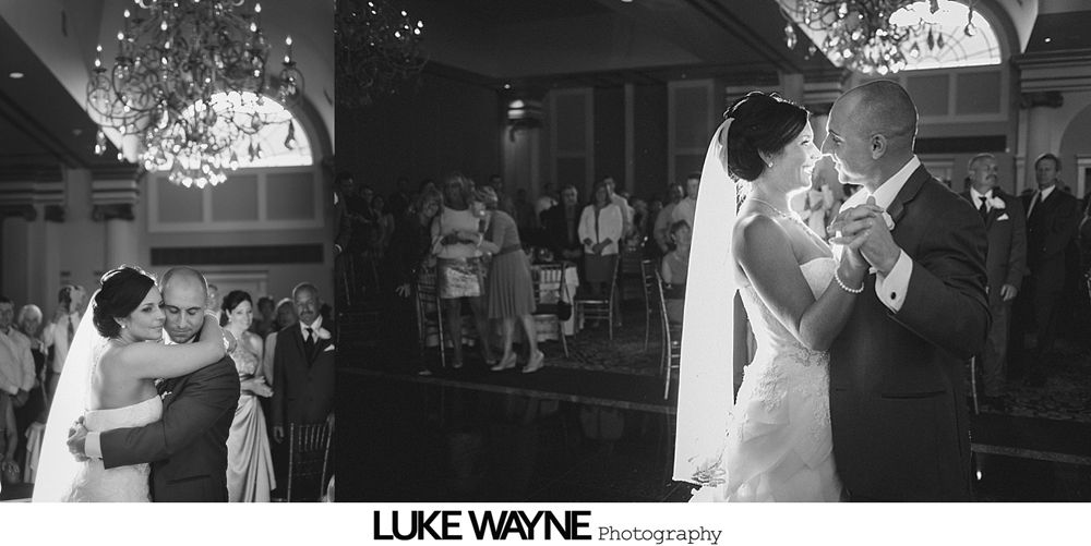 Man dances with a woman at a reception; indoor setting. Woman wears glasses and striped top. Person takes photo.