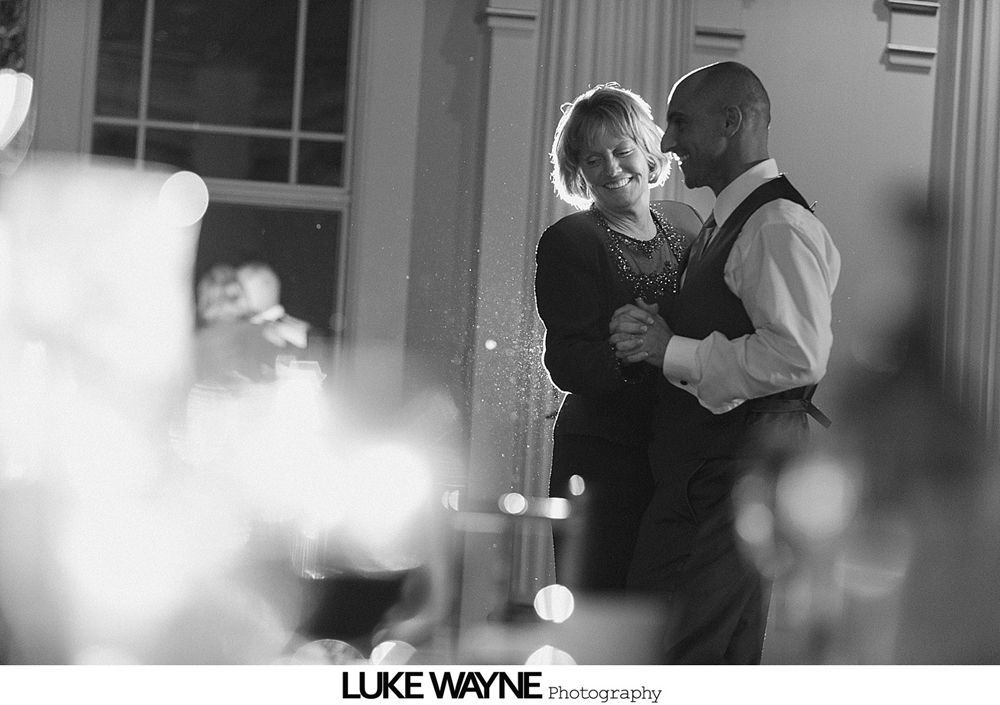 Woman embracing another, both smiling; indoors, event setting.