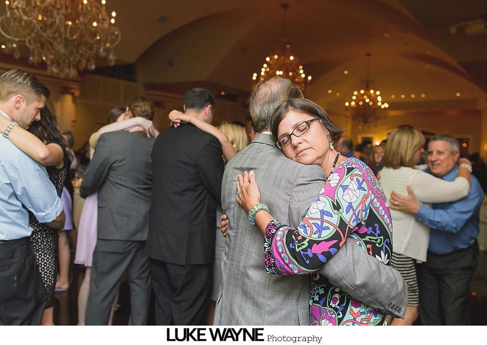 Group photo at a wedding reception. Bride and groom centered, surrounded by guests in formal attire.