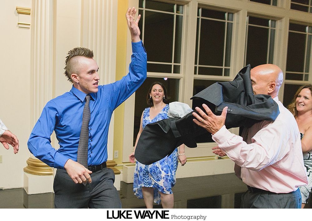 Group photo at a wedding reception. Bride and groom centered, surrounded by guests in formal attire.