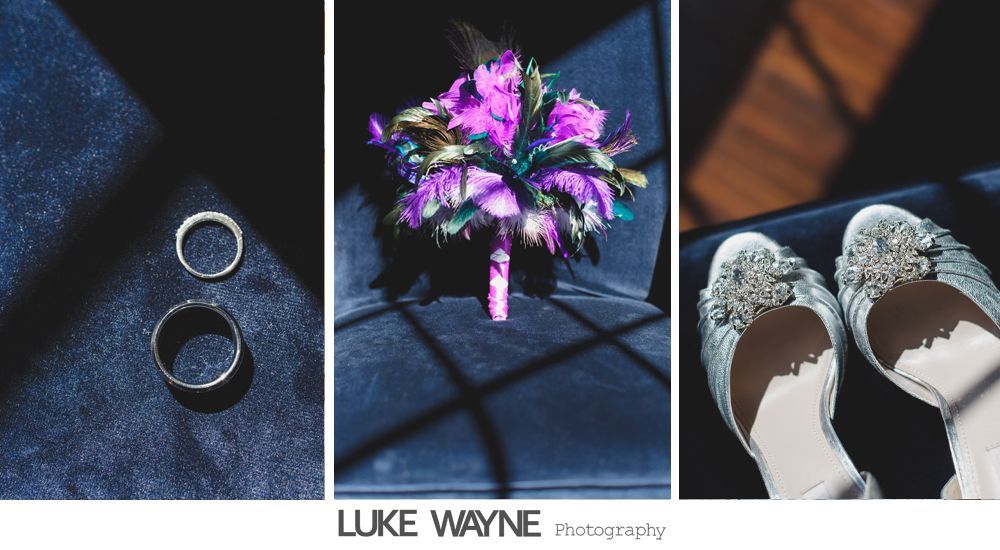 Wedding rings, bouquet, and embellished shoes arranged on dark blue fabric.