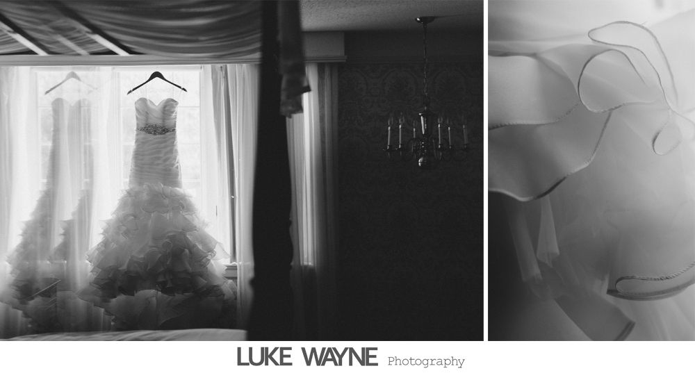 Two wedding dresses hanging in a window, with a chandelier and flowing fabric.