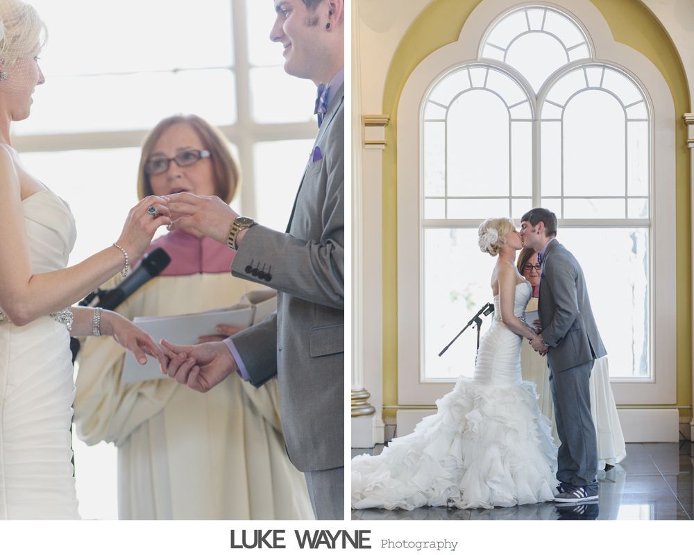 Wedding ceremony: Bride and groom exchanging rings, then kissing in front of large arched window.