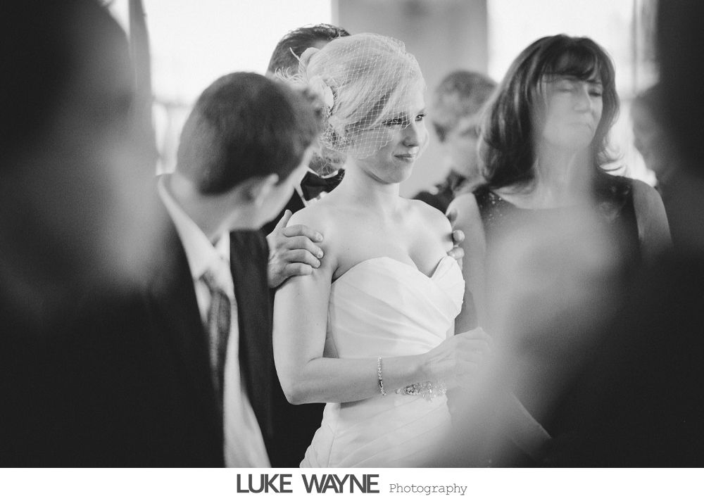 Bride in a strapless gown surrounded by people. Black and white photo.