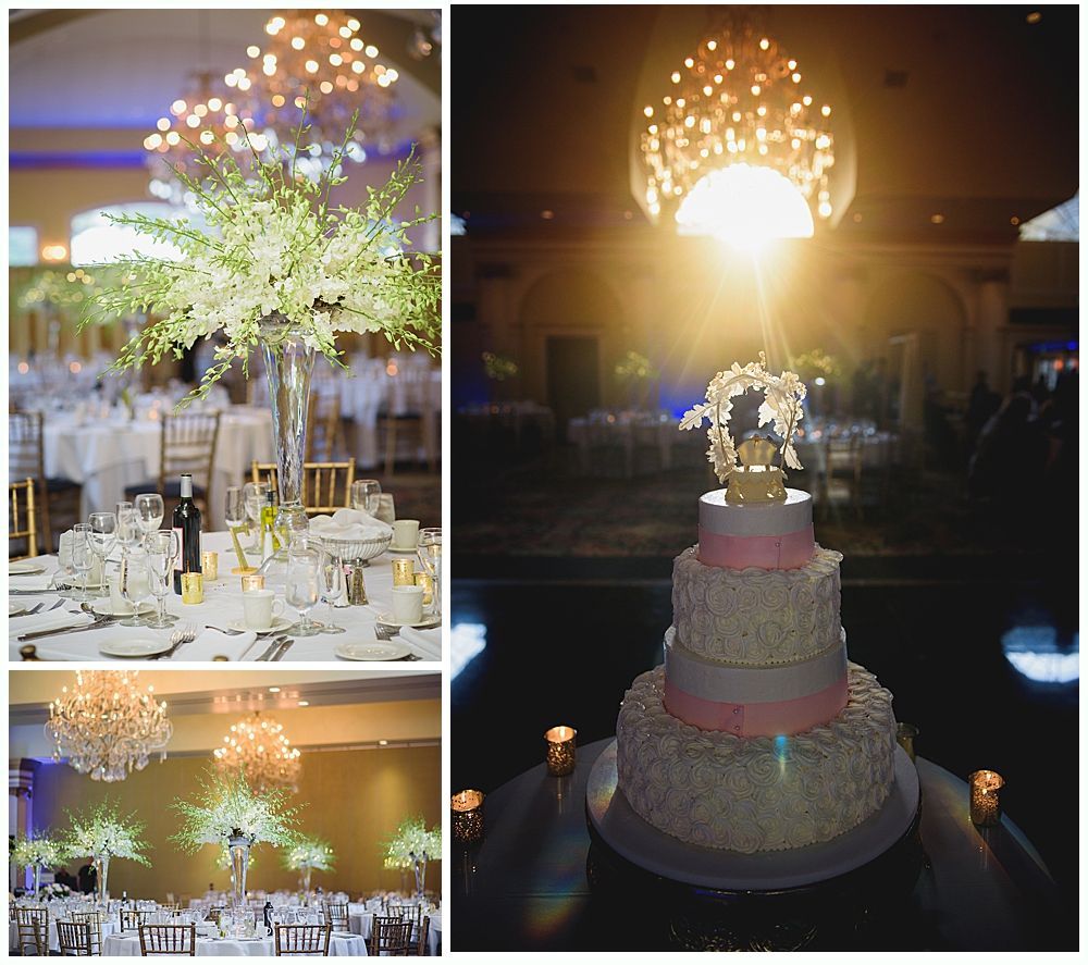 Wedding reception decor: floral centerpieces, tiered cake with topper, chandeliers.