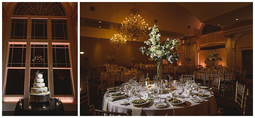 Wedding reception venue with cake in front of large window and table setting with floral centerpiece.