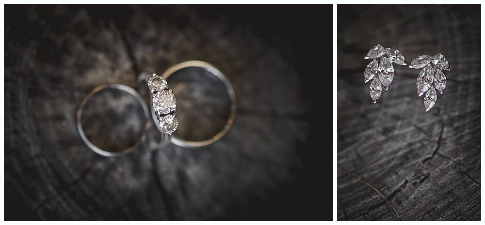 Wedding rings and leaf-shaped earrings on a dark, textured surface, likely wood.