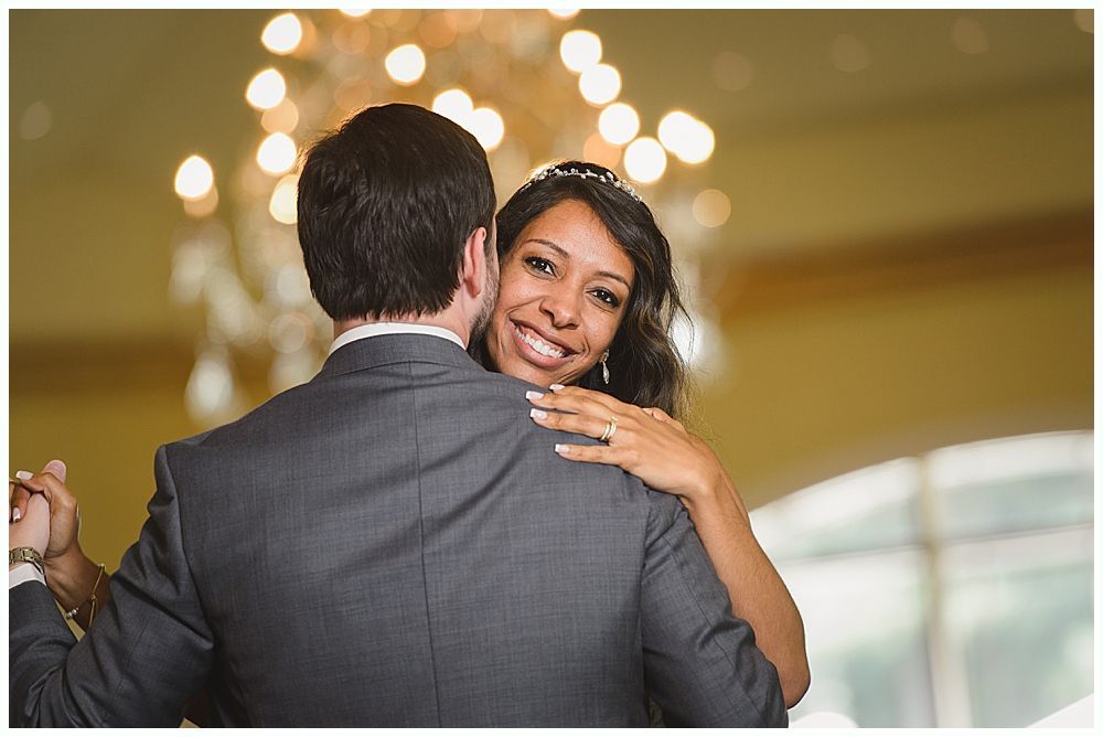 Bride and groom dance at a reception, looking at the camera.