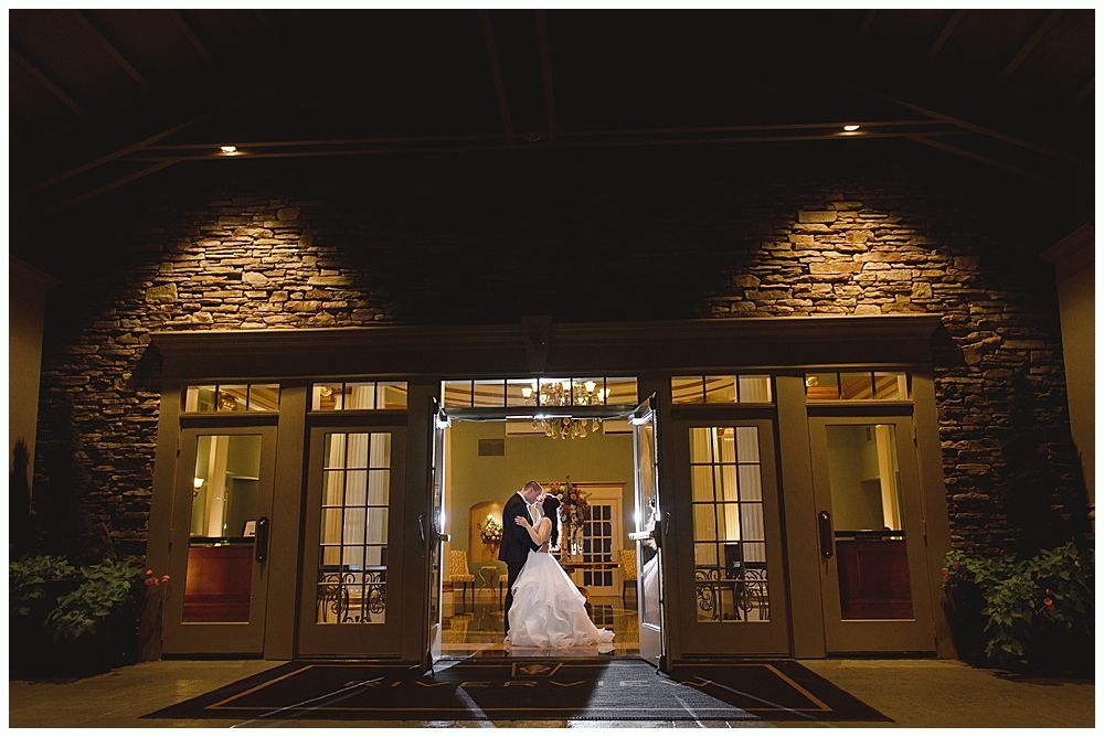 Couple kissing in doorway, illuminated entrance of a building, night.