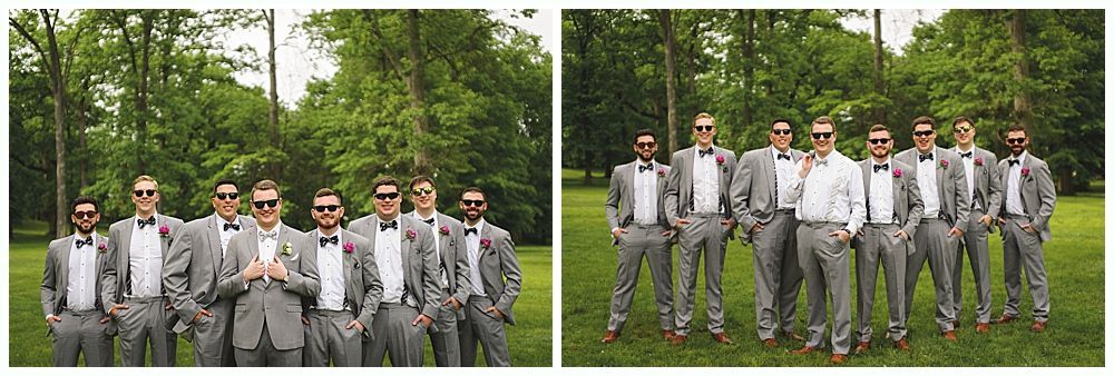 Group of men in gray suits and sunglasses posing outdoors in front of trees.