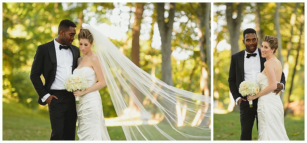 Wedding party smiles for photo outdoors. Bride, groom, bridesmaids, groomsmen, wearing black attire, holding bouquets.