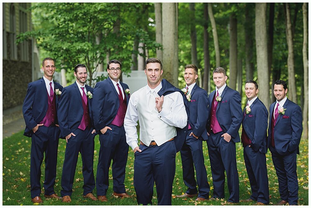 Groomsmen in navy suits with maroon vests and ties, posing outdoors with the groom.