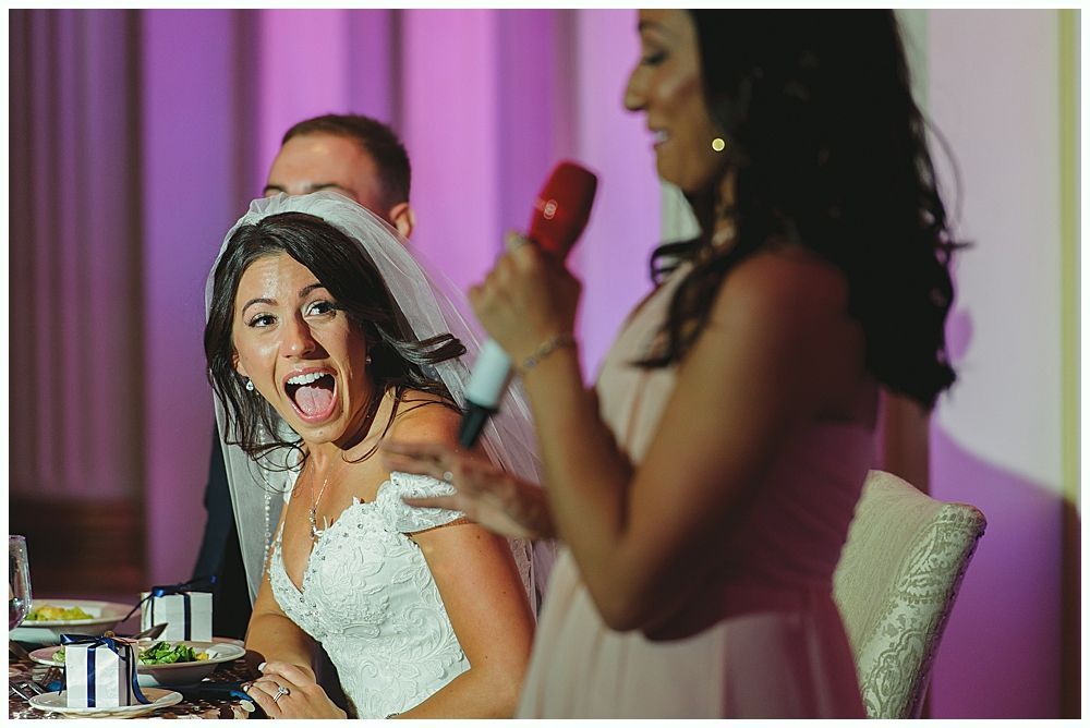 Bride reacts with surprise during a speech at a wedding reception.
