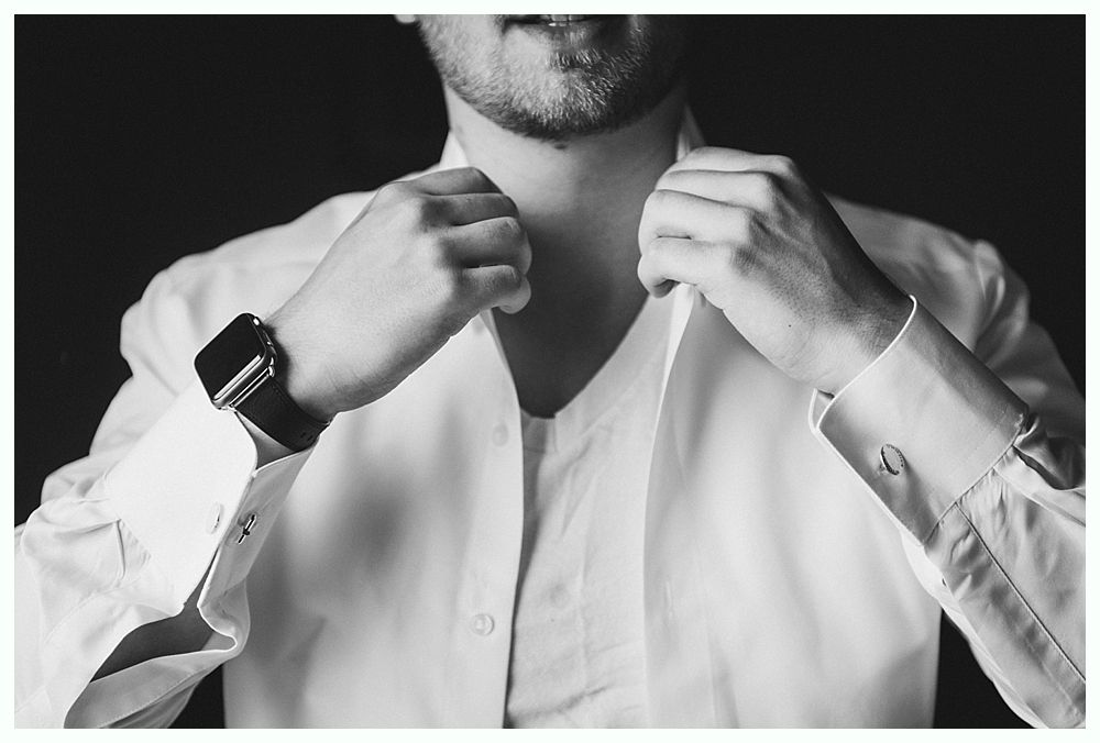 Man adjusting a white dress shirt collar.