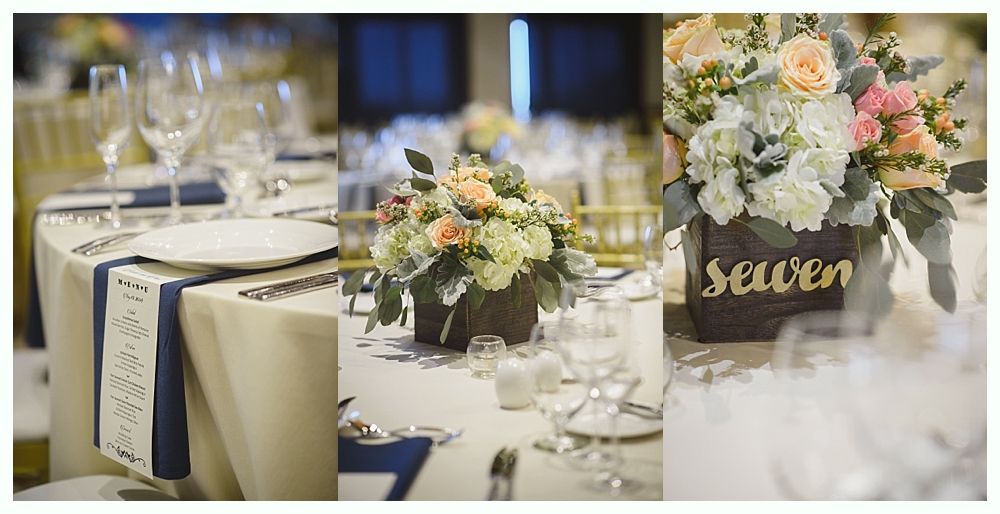 Wedding reception table setting with floral centerpieces and navy blue accents.