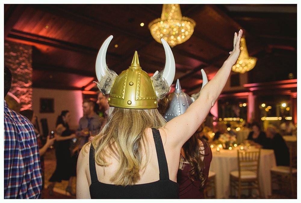 Woman in Viking helmet raises arm, other guests at a party.