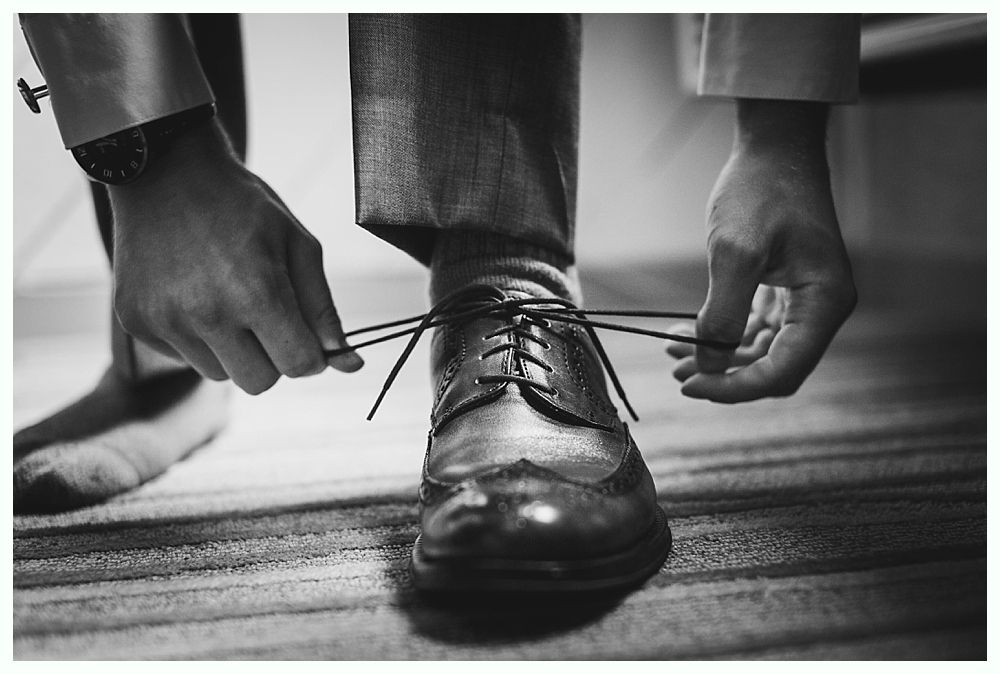Man tying shoelaces on a leather dress shoe, close-up.