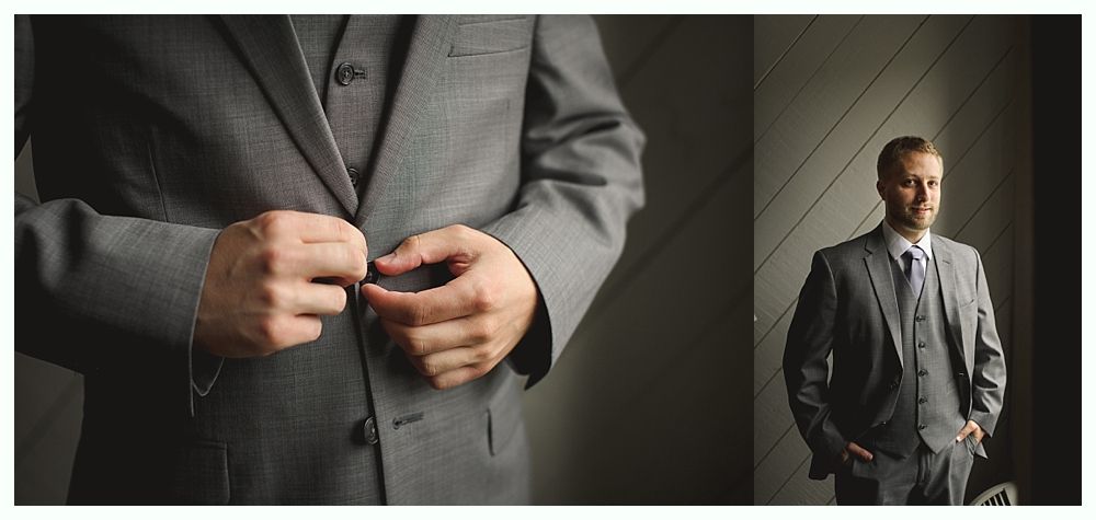 Man in gray suit buttoning his jacket, standing by a window.