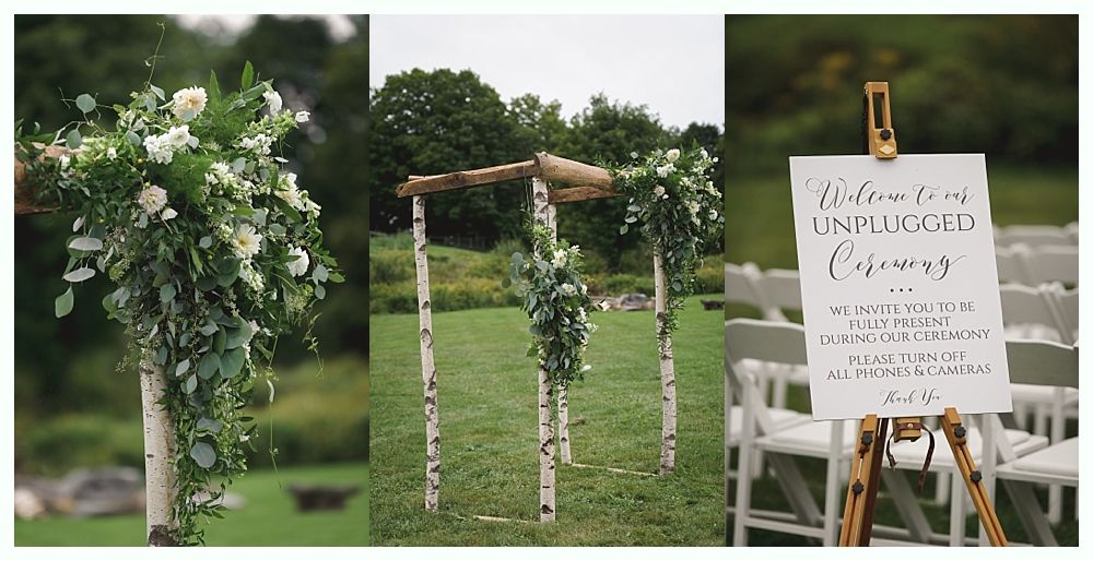 Wedding ceremony setup: birch posts with floral decor, sign reading 